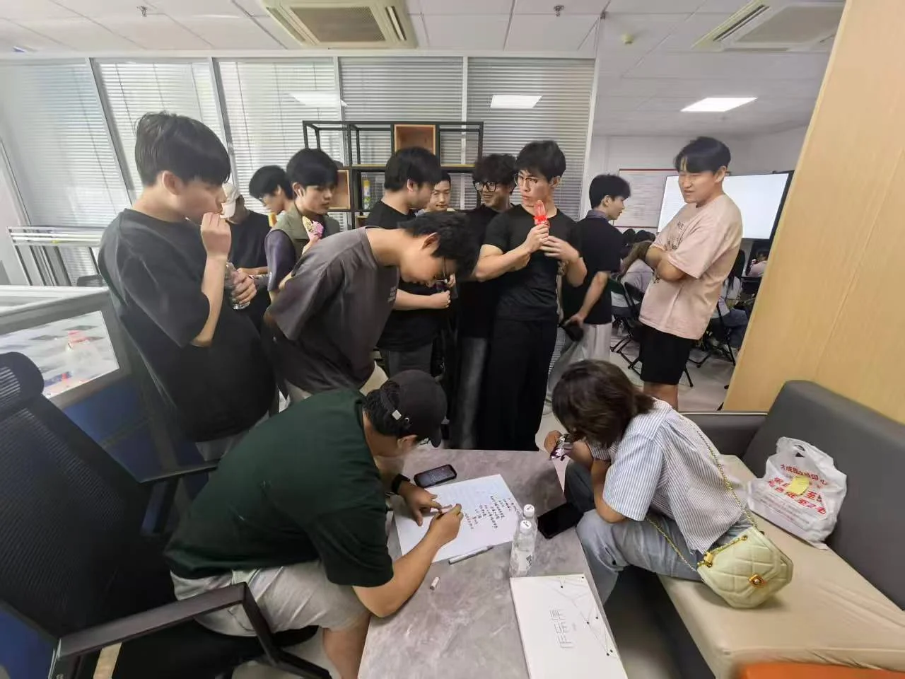 师生围绕桌面上的设计图稿交流讨论